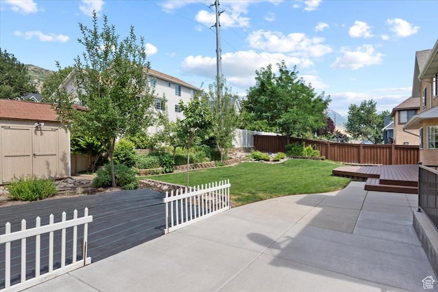 view of patio featuring a deck, an outdoor structure, a storage shed, and a fenced backyard