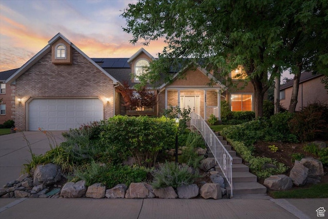 view of front of home featuring concrete driveway, an attached garage, brick siding, and roof mounted solar panels