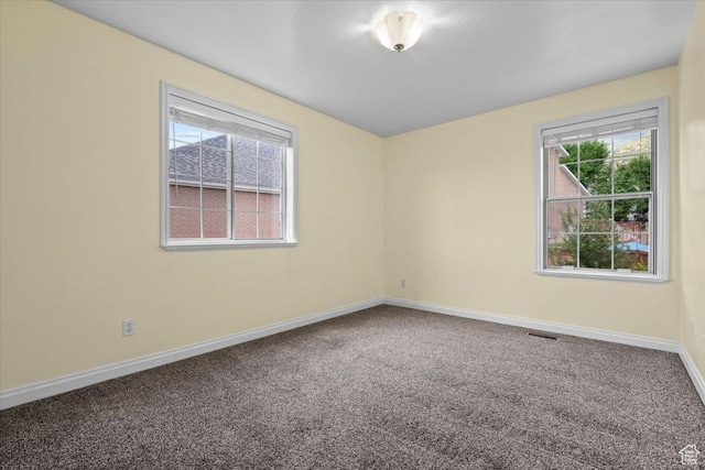 carpeted spare room with visible vents and baseboards