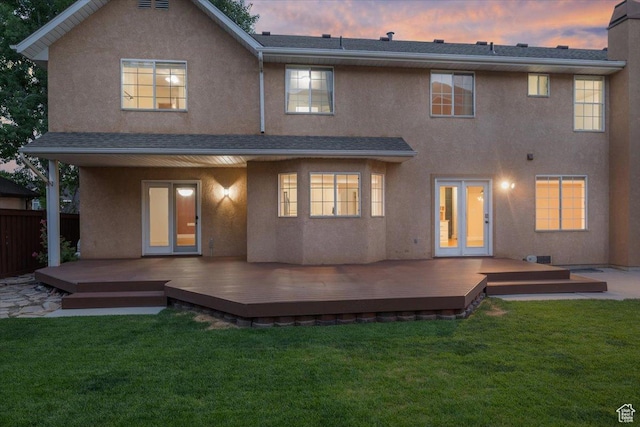 back of house with a lawn, french doors, and stucco siding