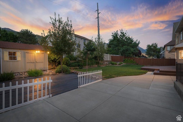view of patio / terrace featuring a storage unit, an outbuilding, a wooden deck, and fence