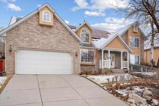 traditional-style house featuring brick siding, solar panels, driveway, and an attached garage