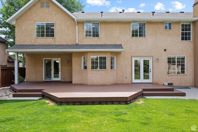 rear view of house featuring french doors, a lawn, a wooden deck, and stucco siding