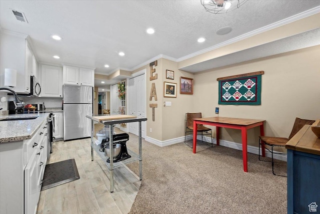 kitchen with visible vents, a sink, white cabinetry, appliances with stainless steel finishes, and crown molding