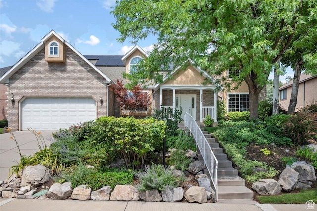 view of front of property with brick siding, stairs, covered porch, a garage, and driveway