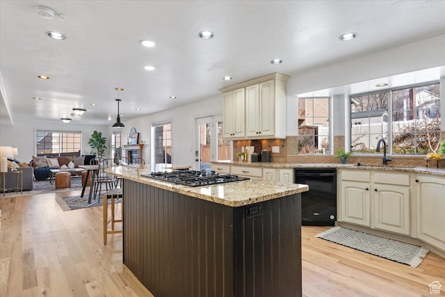 kitchen with cream cabinetry, a kitchen island, light wood-style floors, dishwasher, and stainless steel gas cooktop