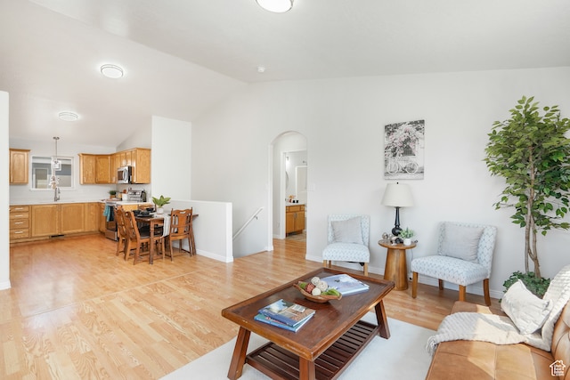 living room featuring light hardwood / wood-style floors, sink, and vaulted ceiling