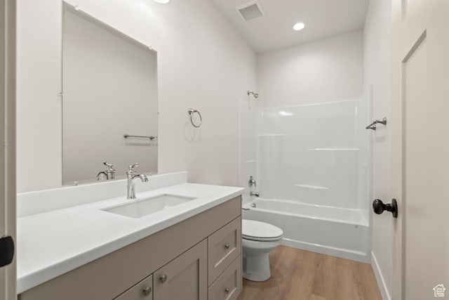 bathroom featuring visible vents, toilet, wood finished floors, vanity, and shower / bath combination