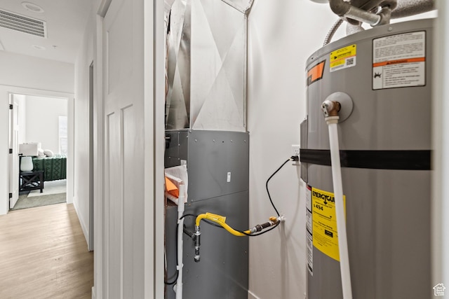 utility room with water heater, visible vents, and heating unit