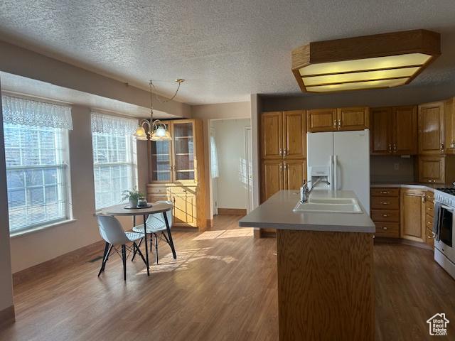 596 Eagle Dr, Preston, ID 83263 - kitchen featuring decorative light fixtures, sink, a kitchen island with sink, white appliances, and light wood-type flooring