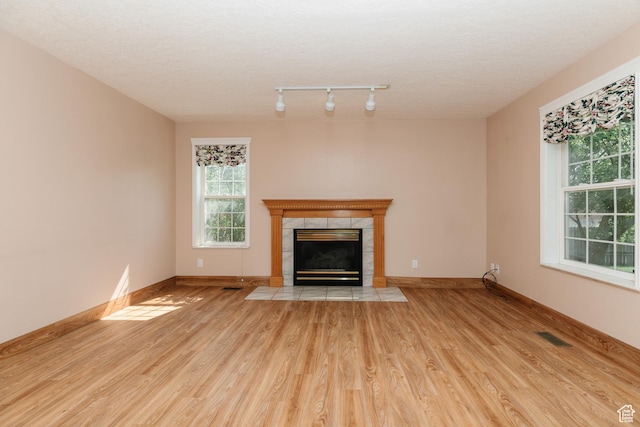 596 Eagle Dr, Preston, ID 83263 - unfurnished living room featuring a tiled fireplace, rail lighting, a textured ceiling, and light wood-type flooring