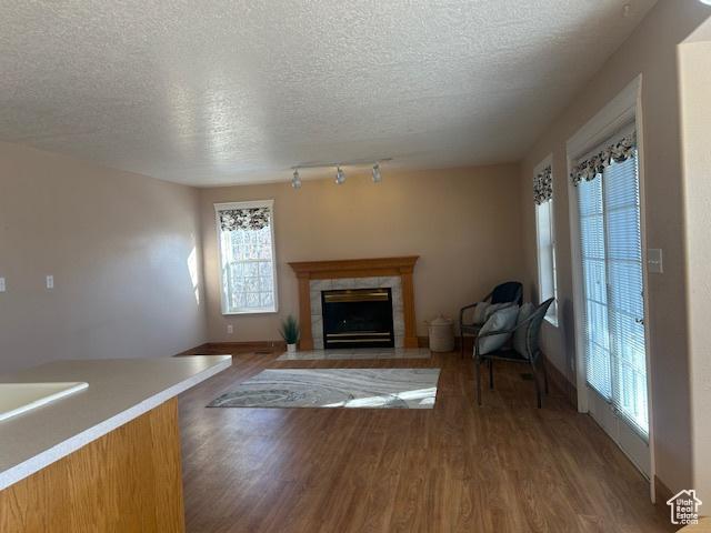 596 Eagle Dr, Preston, ID 83263 - unfurnished living room with dark wood-type flooring, a tiled fireplace, and a textured ceiling