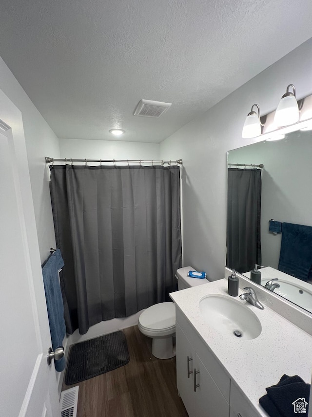 bathroom with hardwood / wood-style floors, a textured ceiling, toilet, and vanity