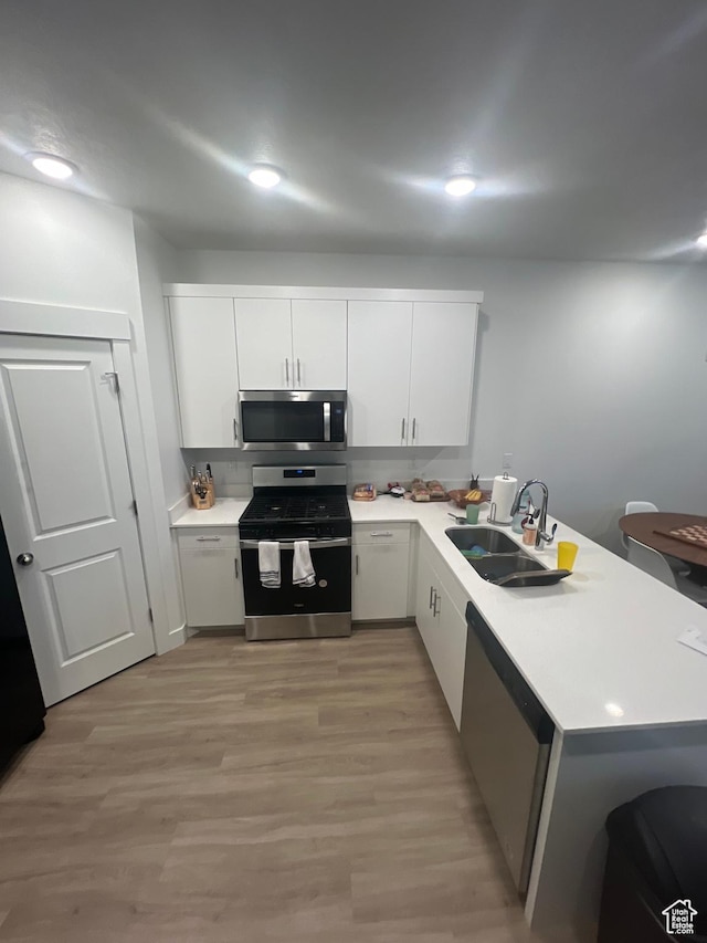 kitchen with sink, white cabinets, kitchen peninsula, and stainless steel appliances
