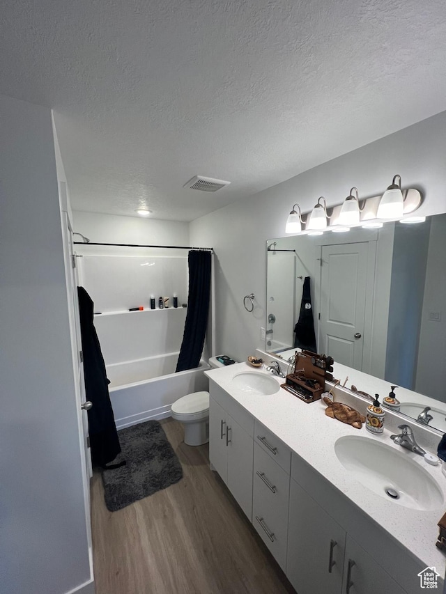 full bathroom with vanity, shower / tub combo, a textured ceiling, and wood-type flooring
