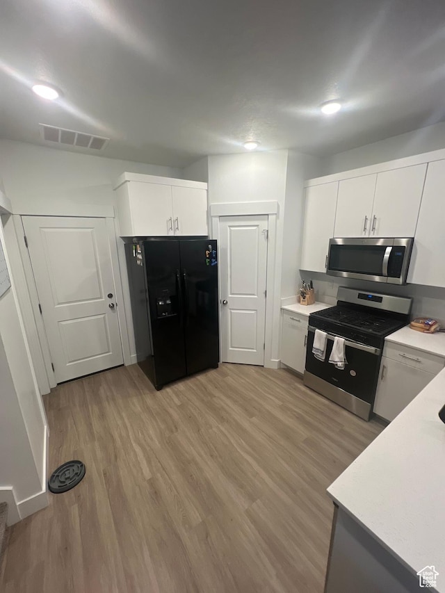 kitchen featuring white cabinets, light hardwood / wood-style flooring, and appliances with stainless steel finishes