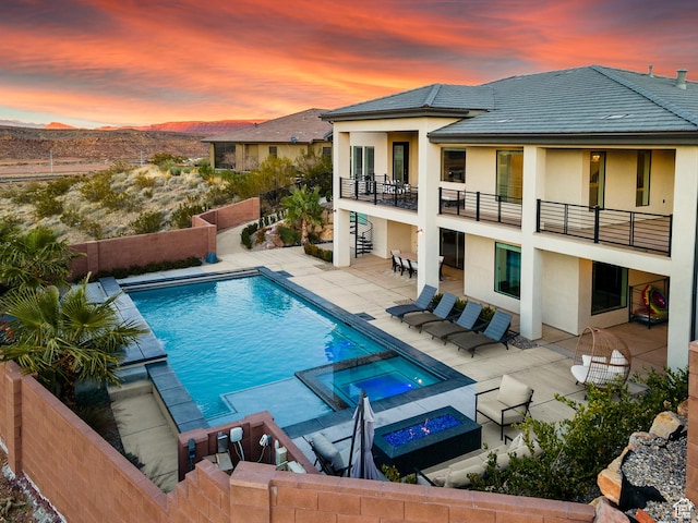 pool at dusk with a fire pit, a patio, and an in ground hot tub