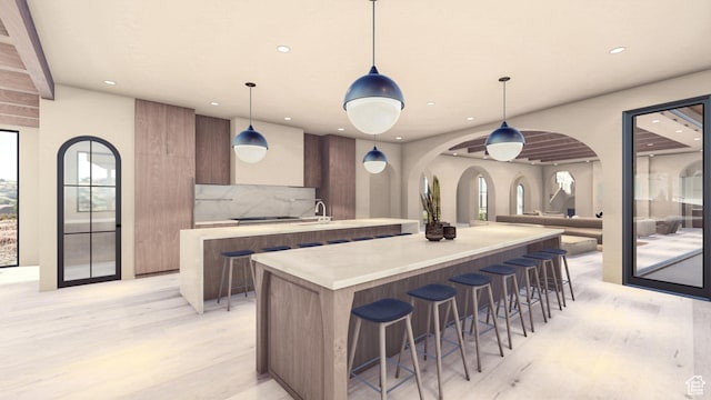 1272 N Hillside Way, Santa Clara, UT 84765 - kitchen with a breakfast bar, a center island with sink, pendant lighting, light hardwood / wood-style floors, and backsplash