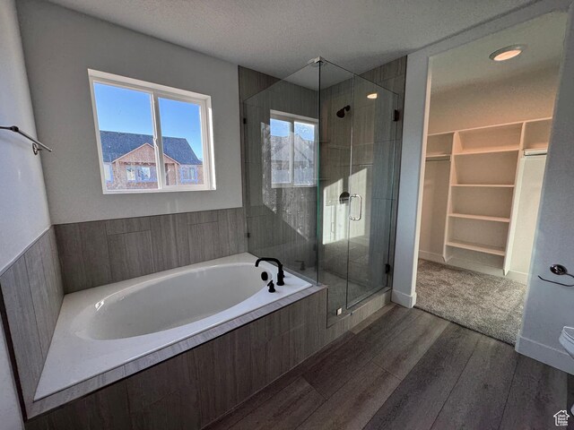 426 E Redwood Ln Unit 119, Grantsville, UT 84029 - full bath with wood finished floors, a stall shower, a walk in closet, a garden tub, and a textured ceiling