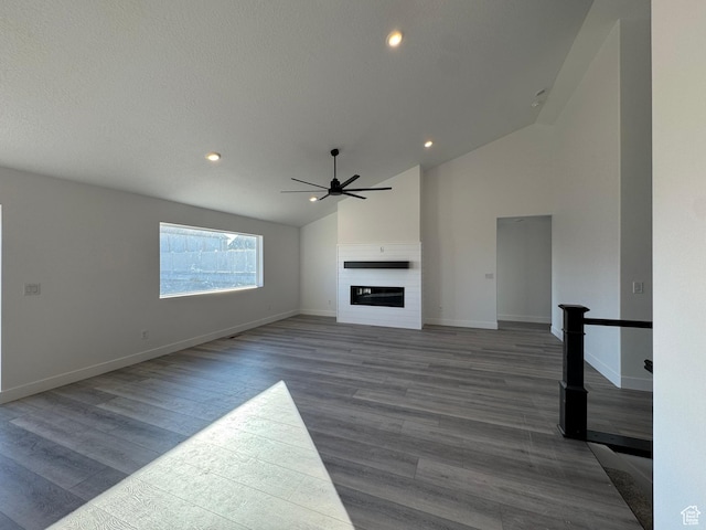 426 E Redwood Ln Unit 119, Grantsville, UT 84029 - unfurnished living room with lofted ceiling, wood finished floors, ceiling fan, a glass covered fireplace, and baseboards