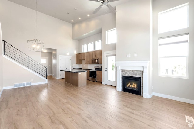 9829 N Aaron Ave Unit 213, Eagle Mountain, UT 84005 - kitchen featuring decorative light fixtures, light hardwood / wood-style flooring, an island with sink, a towering ceiling, and stainless steel appliances