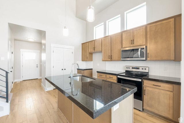 9829 N Aaron Ave Unit 213, Eagle Mountain, UT 84005 - kitchen with sink, decorative light fixtures, appliances with stainless steel finishes, an island with sink, and a towering ceiling