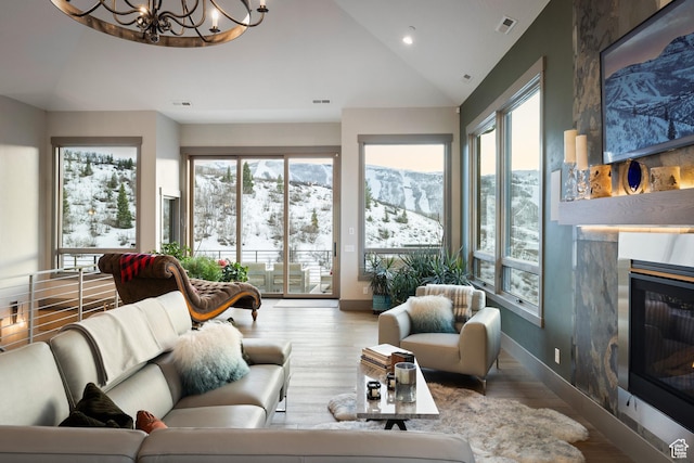 1310 Mellow Rd, Park City, UT 84060 - living room featuring wood finished floors, an inviting chandelier, a glass covered fireplace, and a healthy amount of sunlight