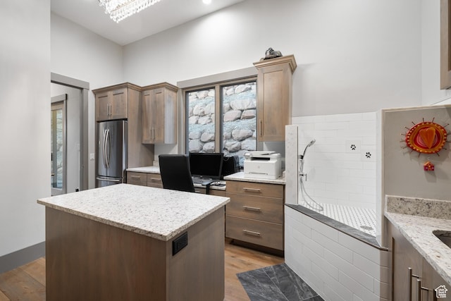 1310 Mellow Rd, Park City, UT 84060 - kitchen with light wood-type flooring, stainless steel refrigerator, a center island, and light stone countertops