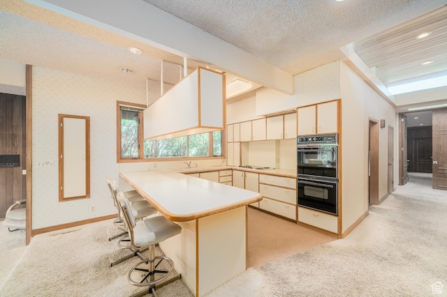 975 N 1600 E, Logan, UT 84321 - kitchen featuring a peninsula, dobule oven black, wallpapered walls, white cooktop, and light colored carpet