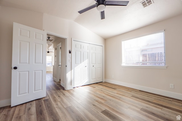 unfurnished bedroom featuring lofted ceiling, a closet, ceiling fan, and light wood-type flooring