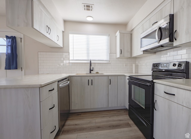 kitchen featuring tasteful backsplash, sink, stainless steel appliances, and light wood-type flooring
