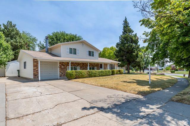 1591 N Marilyn Dr, Syracuse, UT 84075 - view of front of home featuring covered porch, a front yard, brick siding, concrete driveway, and an attached garage