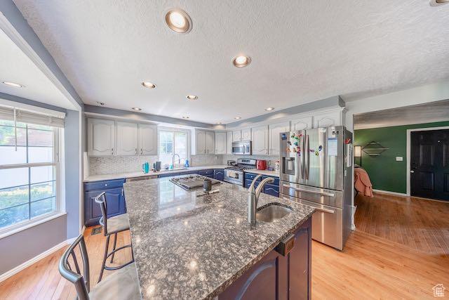 1591 N Marilyn Dr, Syracuse, UT 84075 - kitchen with appliances with stainless steel finishes, a sink, a kitchen island with sink, baseboards, and light wood-type flooring