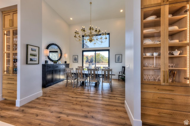 dining area with baseboards, a notable chandelier, high vaulted ceiling, and wood finished floors