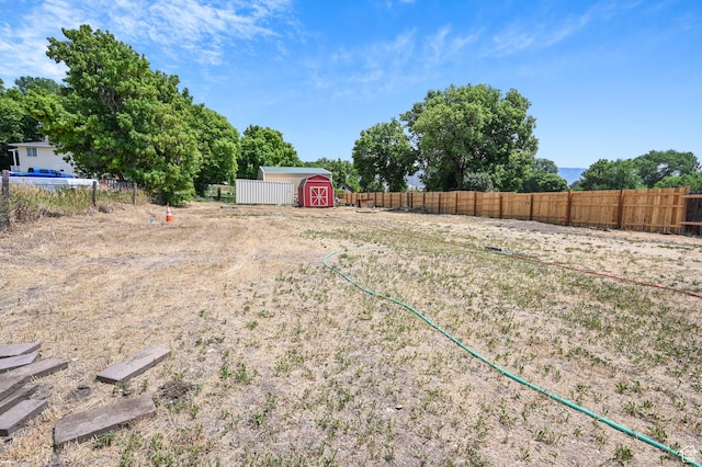 view of yard featuring an outdoor structure, fence, and a storage shed