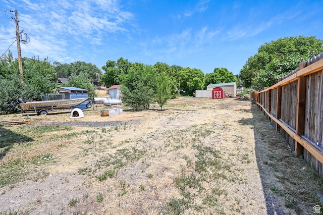 view of yard with an outdoor structure, fence, and a storage shed
