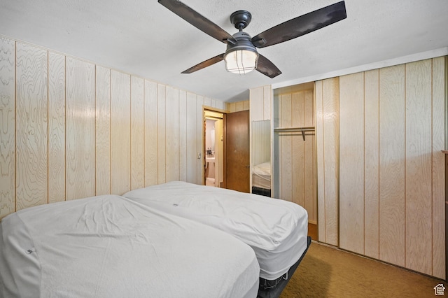 bedroom featuring carpet flooring, a ceiling fan, and wooden walls