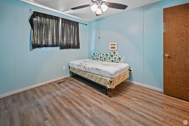 bedroom featuring baseboards, visible vents, wood finished floors, and a ceiling fan