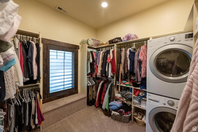 clothes washing area with carpet floors, stacked washing maching and dryer, visible vents, and laundry area