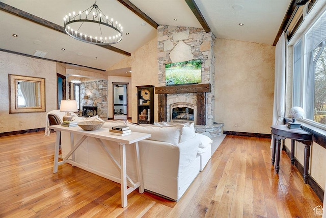 living room with light wood finished floors, a fireplace, a chandelier, and beam ceiling