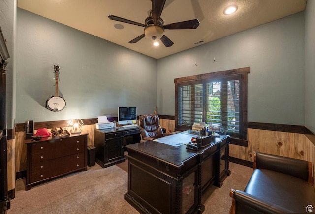 home office featuring ceiling fan, wood walls, wainscoting, and light carpet