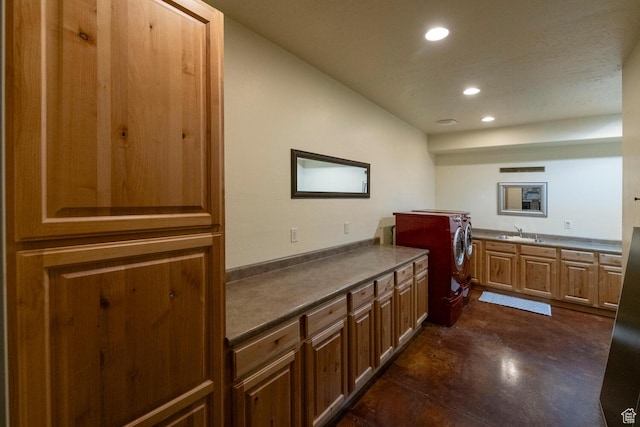 kitchen with dark countertops, concrete floors, a sink, and recessed lighting
