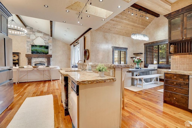 kitchen with light wood-style flooring, a fireplace, a sink, open floor plan, and beam ceiling