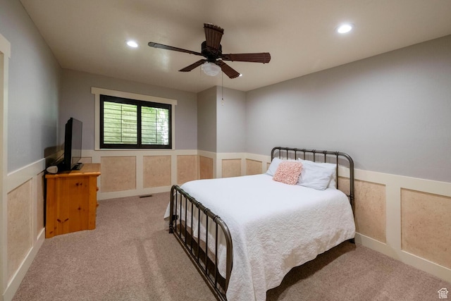 carpeted bedroom with a decorative wall, a wainscoted wall, recessed lighting, visible vents, and a ceiling fan