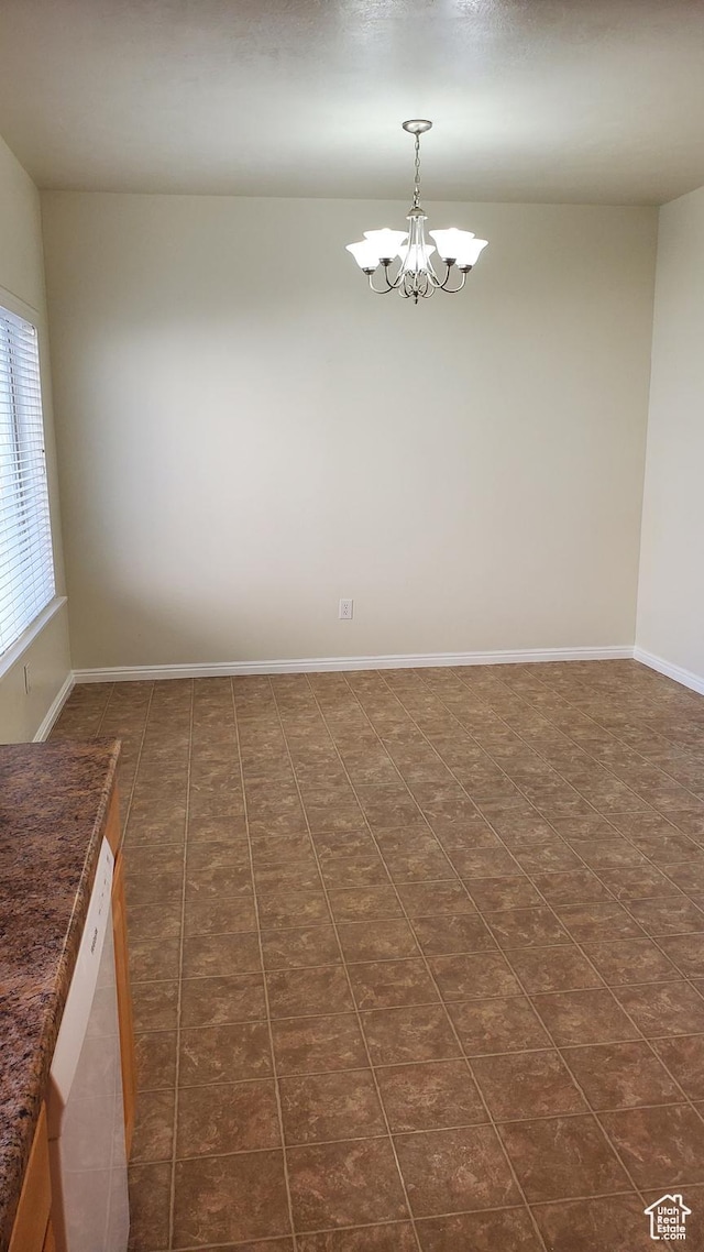 spare room with a chandelier and baseboards