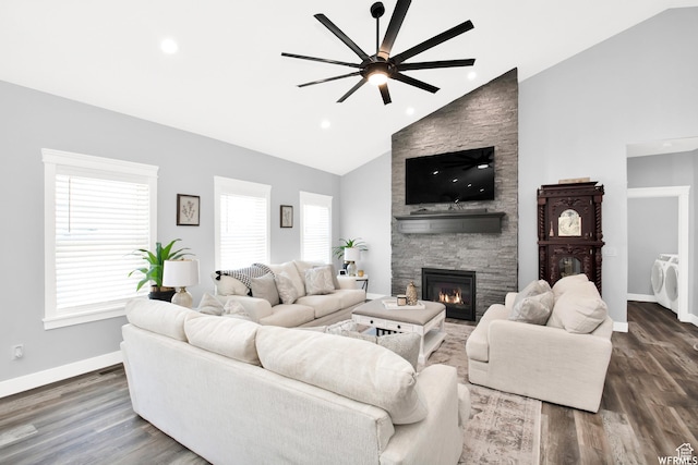 living room featuring a stone fireplace, a healthy amount of sunlight, and dark hardwood / wood-style floors