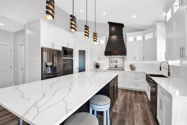 kitchen with premium range hood, black appliances, white cabinets, a kitchen island, and decorative light fixtures