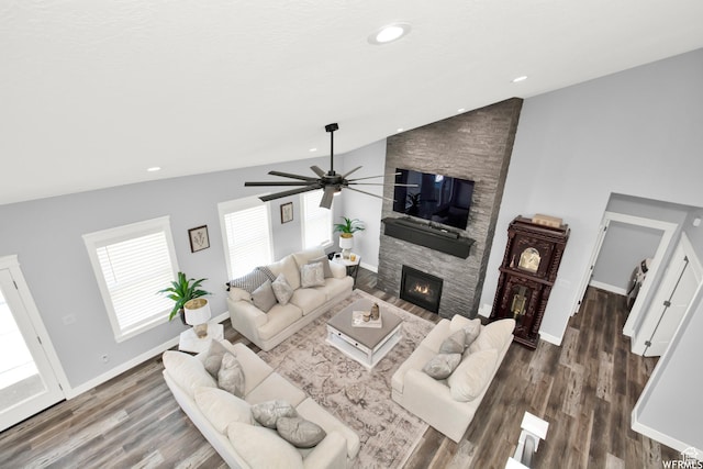 living room with ceiling fan, lofted ceiling, a stone fireplace, and dark hardwood / wood-style flooring
