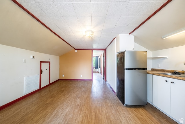 89 W 100 S, Kanab, UT 84741 - kitchen featuring stainless steel fridge, light wood-type flooring, lofted ceiling, white cabinetry, and ornamental molding