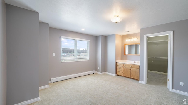 401 N Fairgrounds Rd, Price, UT 84501 - unfurnished bedroom featuring sink, a baseboard heating unit, a walk in closet, light colored carpet, and a closet